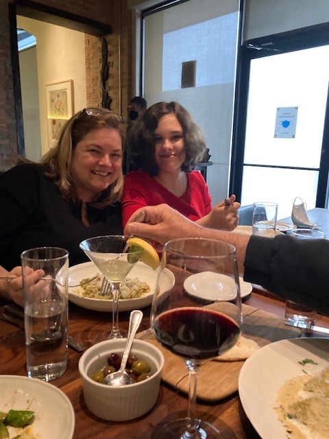 Two women sitting at a table with food.