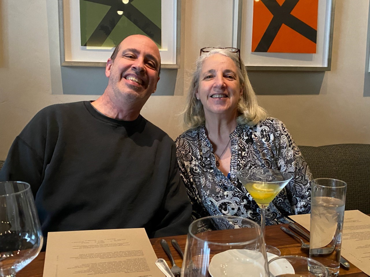 A man and woman sitting at a table with glasses of wine.