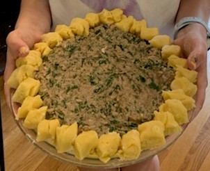 A person holding a large dish of food.