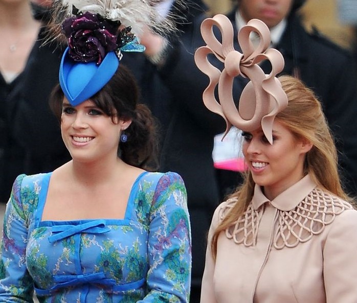 Two women in fancy hats standing next to each other.