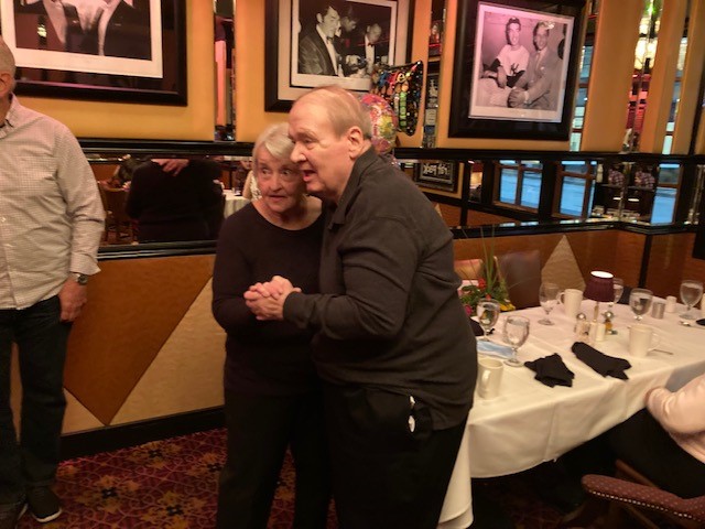 A man and woman hugging in front of a table.