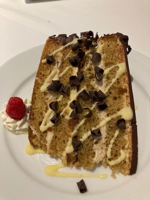 A piece of cake with chocolate chips and whipped cream.