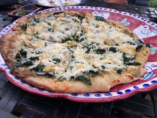 A pizza sitting on top of a red and white plate.