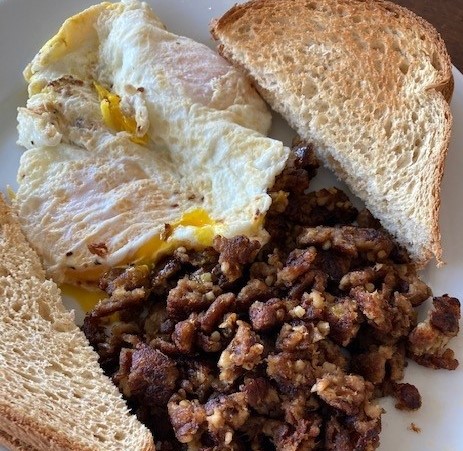 A plate of food with meat and an egg on it.