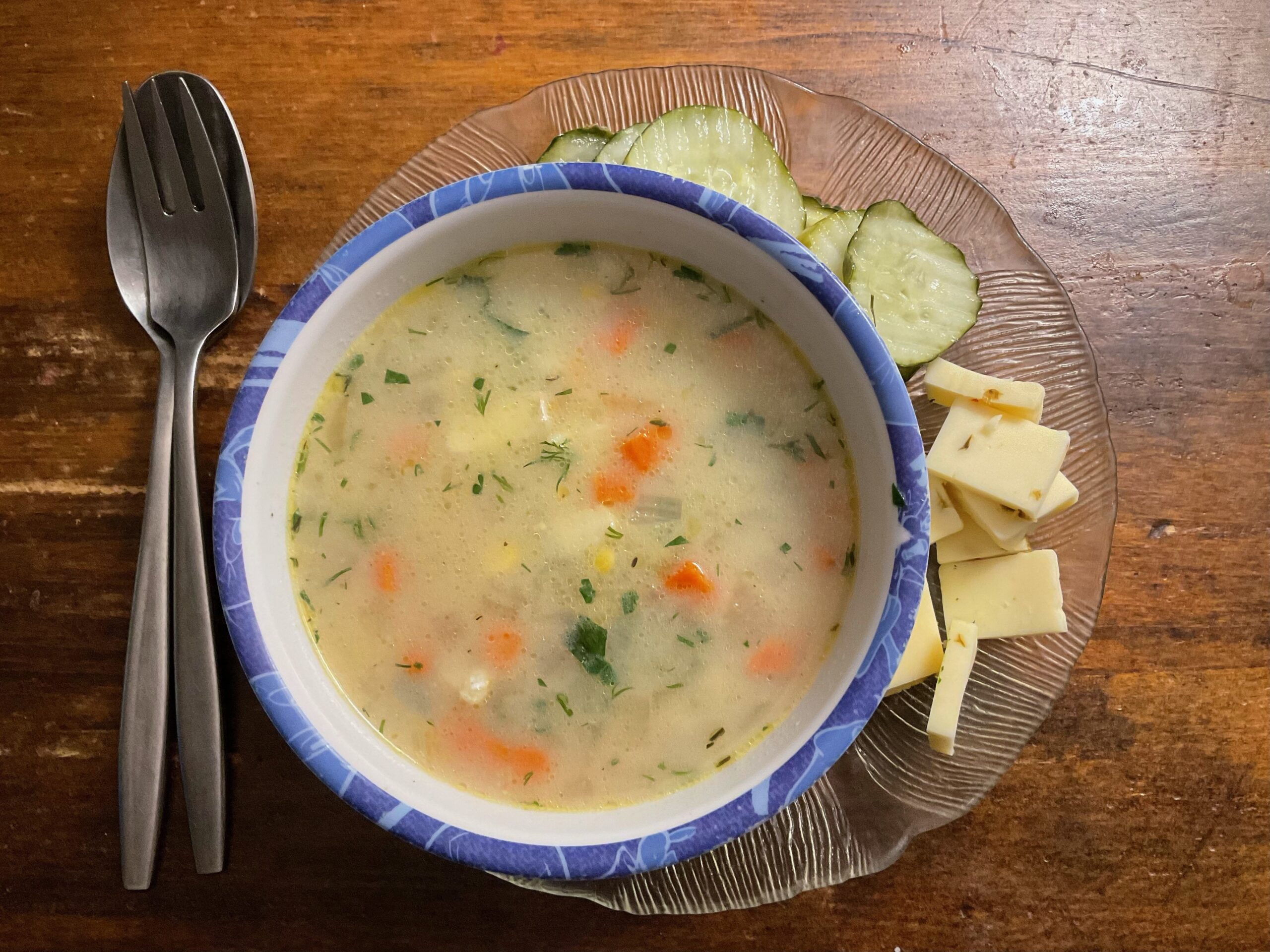 A bowl of soup with crackers and cheese on the side.