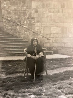 A woman sitting in an old chair with her cane.