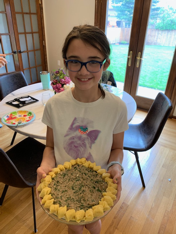 A girl holding a plate of food in front of her face.