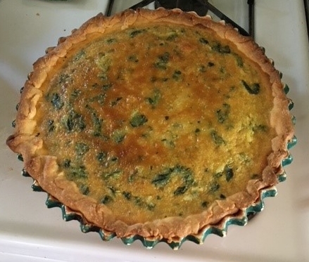 A quiche is sitting on the stove top.