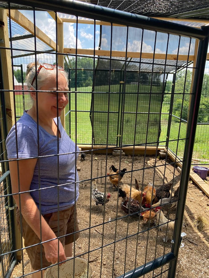 A woman standing in front of chickens inside a cage.