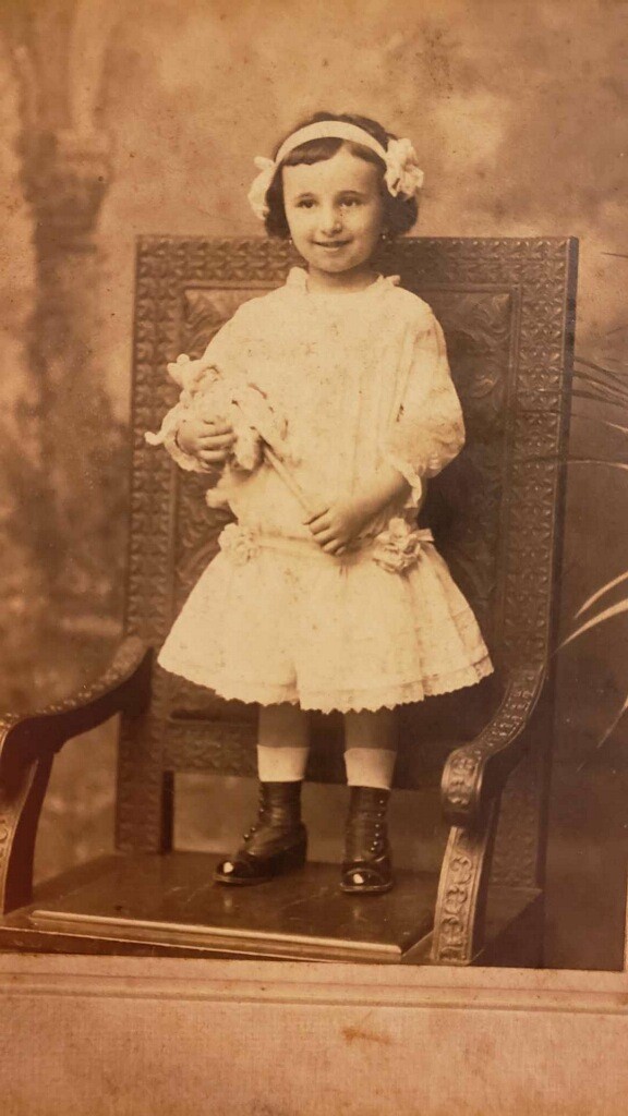 A young girl in white dress holding a stuffed animal.