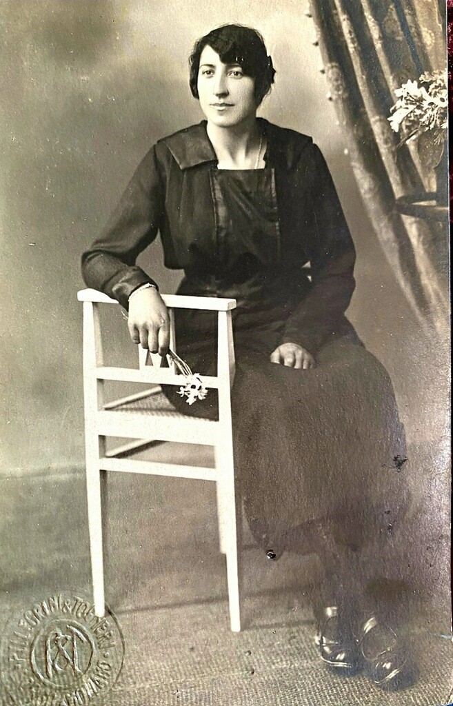 A woman sitting in a chair wearing a black dress.