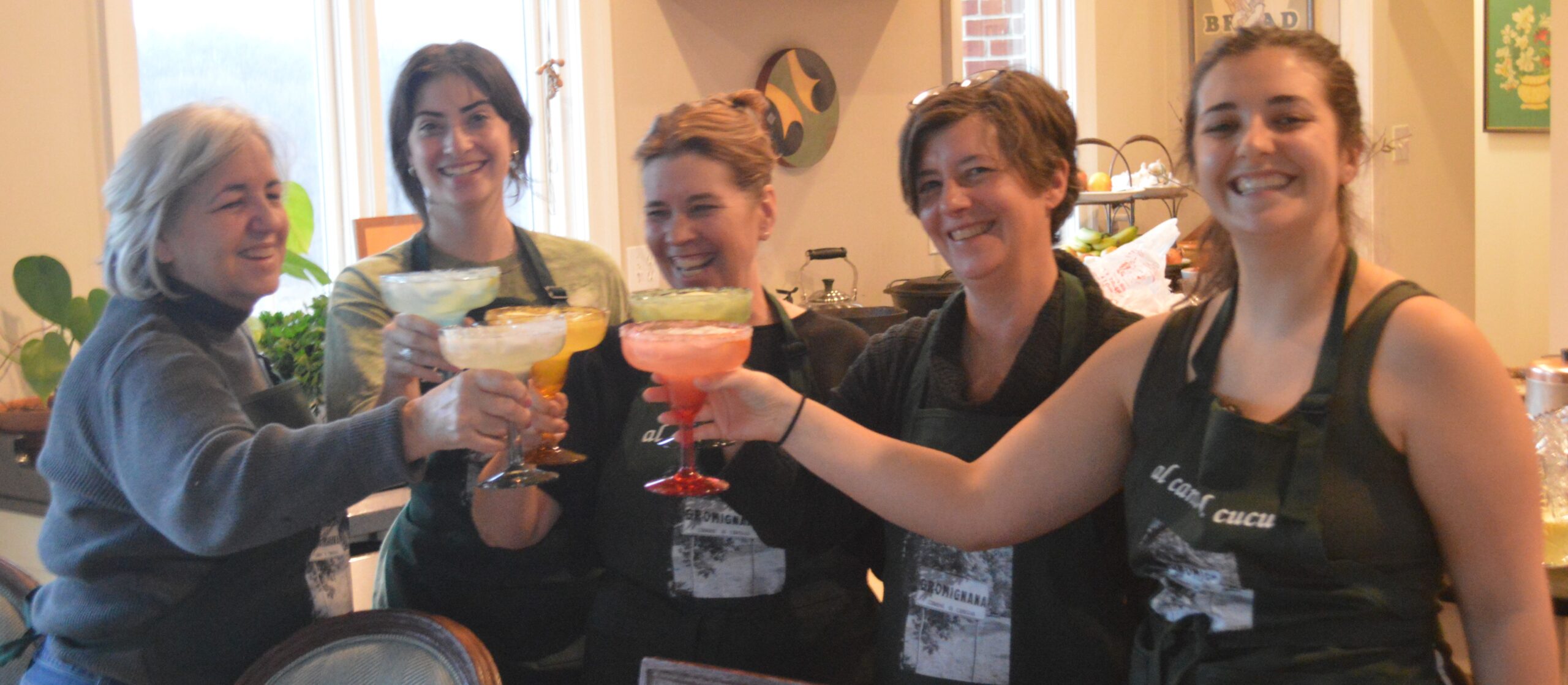 Three women holding glasses of drinks in their hands.